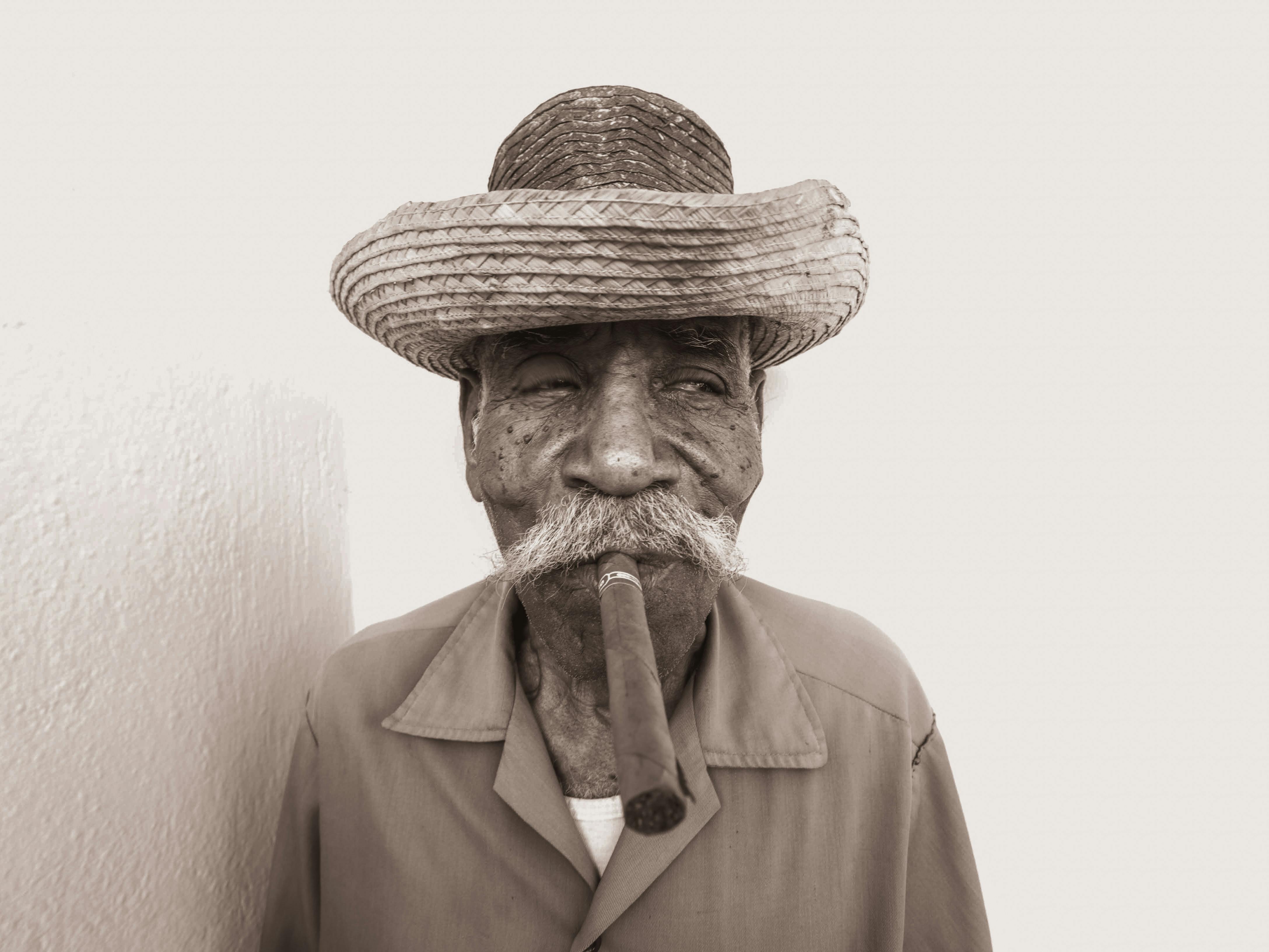 an elderly man in brown straw hat smoking tobacco