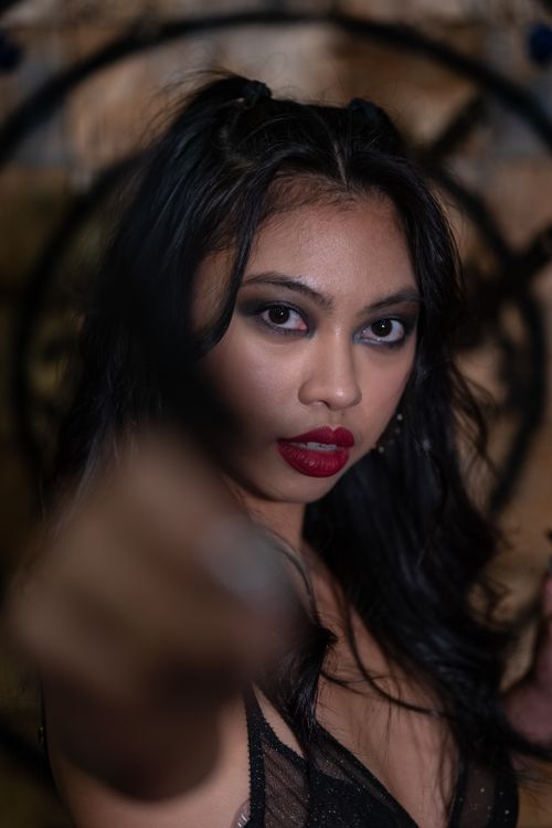 Free Close-up portrait of an Asian woman with striking makeup and intense expression in dim lighting. Stock Photo