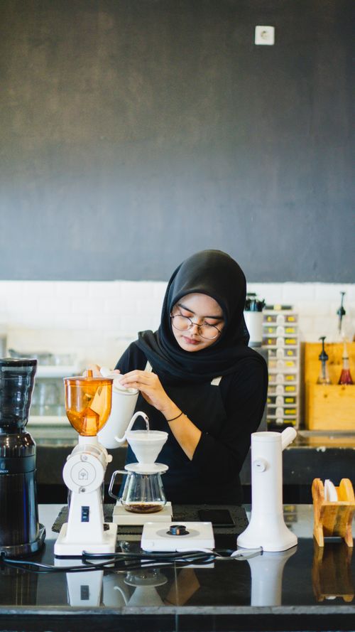 Free Barista in hijab brewing coffee in a Madiun café, Indonesia. Stock Photo