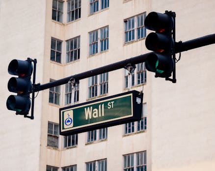 Traffic lights and Wall St sign in cityscape, symbolizing finance hub.