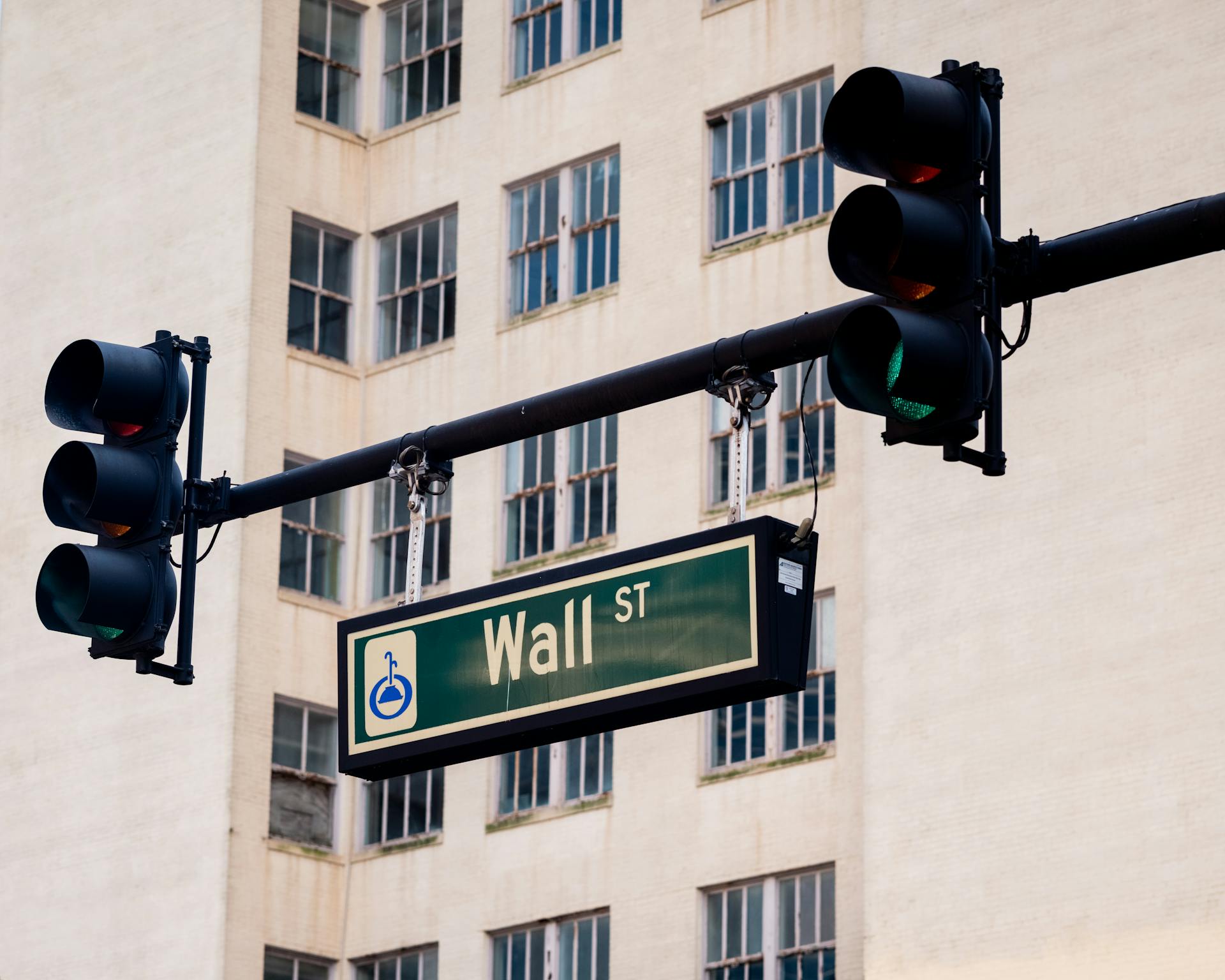 Traffic lights and Wall St sign in cityscape, symbolizing finance hub.