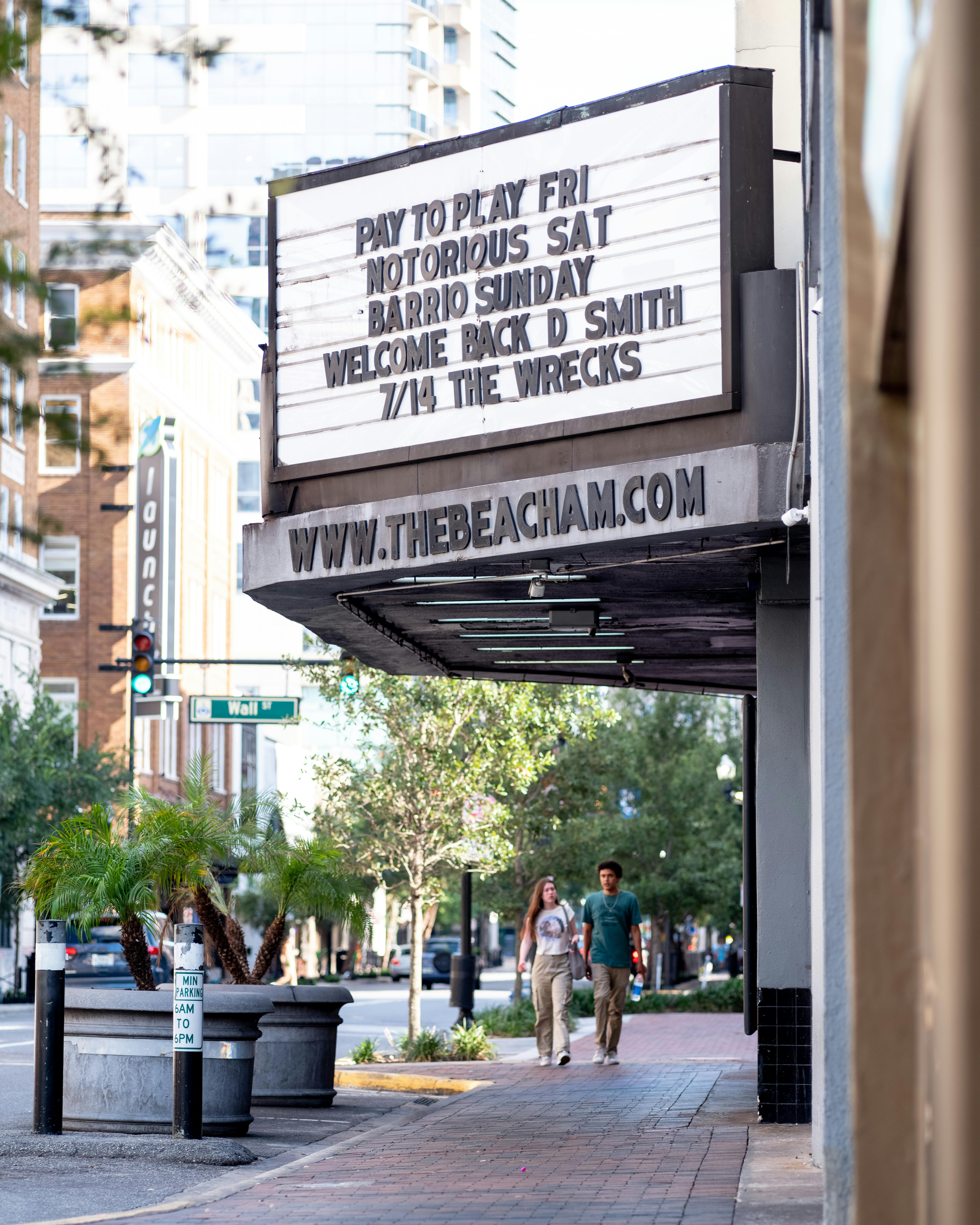 Free Street view featuring a marquee displaying event details with people walking nearby. Stock Photo