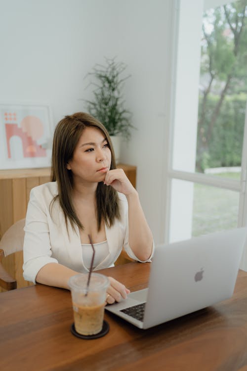 Woman in White Blazer Sitting In Front of a Laptop 