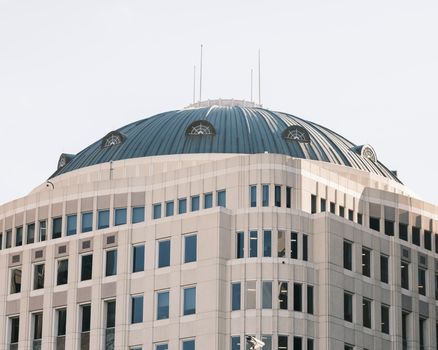 A striking modern building featuring a large dome roof and numerous windows against a clear sky.