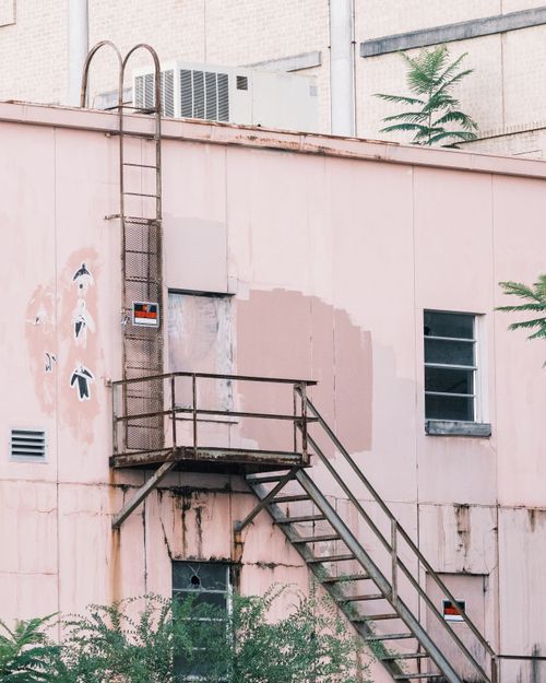 Free An angled view of an urban fire escape on a weathered pink building facade. Stock Photo