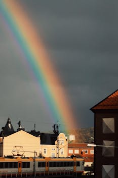 A vibrant rainbow arches over Jönköping cityscape during an autumn evening.
