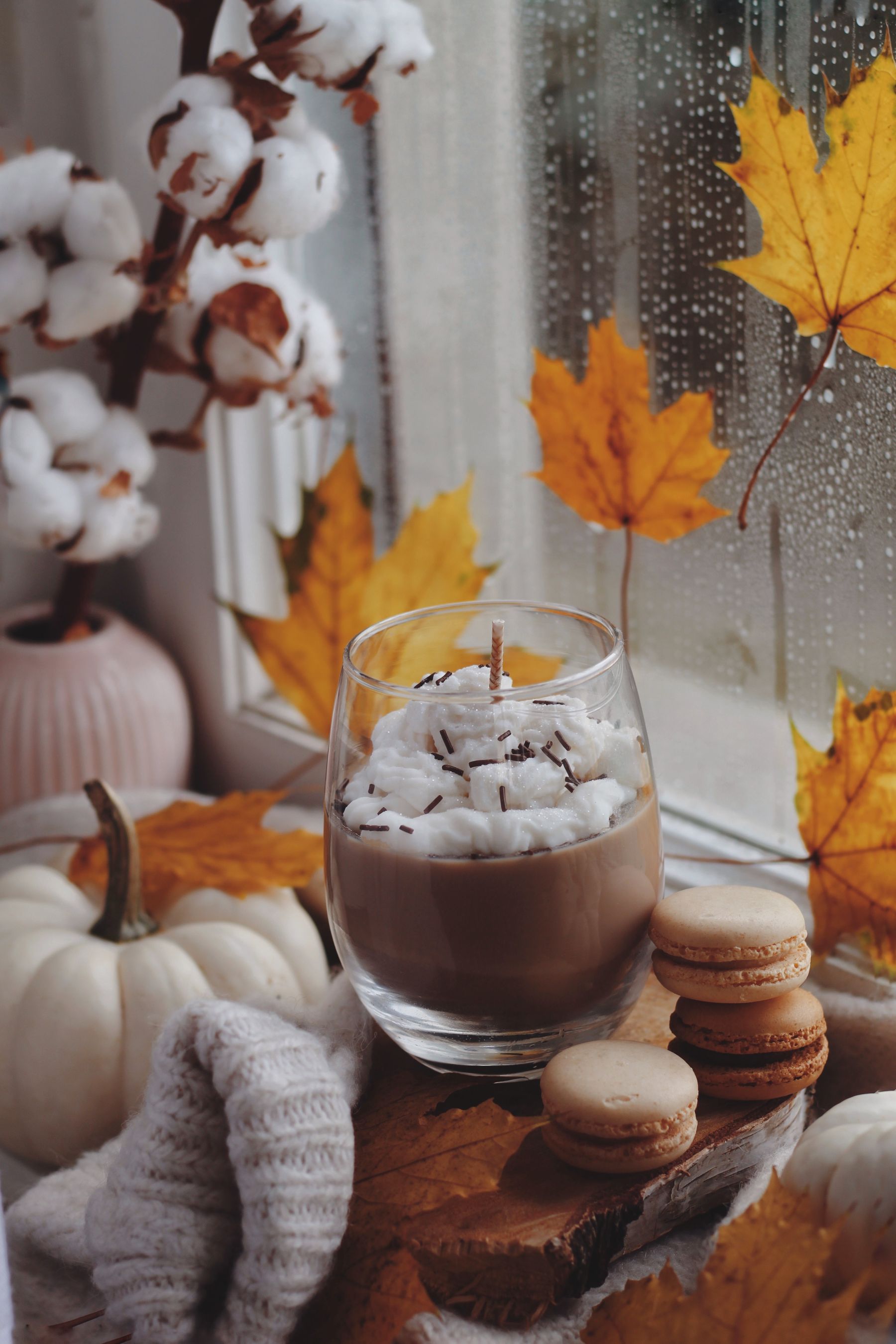 Rainy autumn window with warm drink, pumpkin and fallen leaves