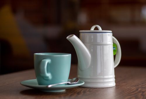 Free A simple and classic composition featuring a teapot and cup in soft lighting on a wooden table. Stock Photo