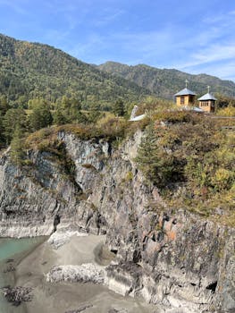 A picturesque chapel on a cliff with mountain and forest views in Altai, Russia.