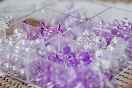 Organized clear and purple beads in a transparent container, ideal for crafting.