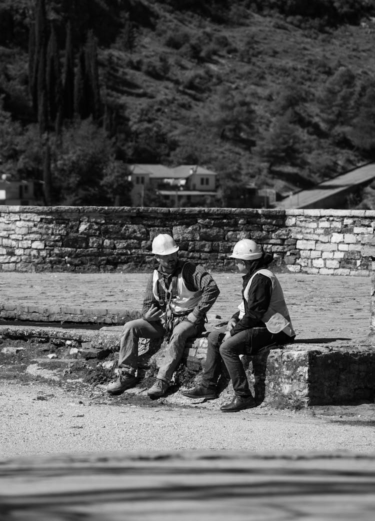 Grayscale Photo Of Construction Workers Talking To Each Other