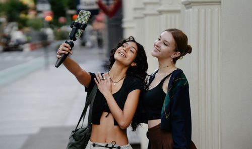 Free Two women enjoying a selfie moment on an urban street, capturing fun and friendship. Stock Photo