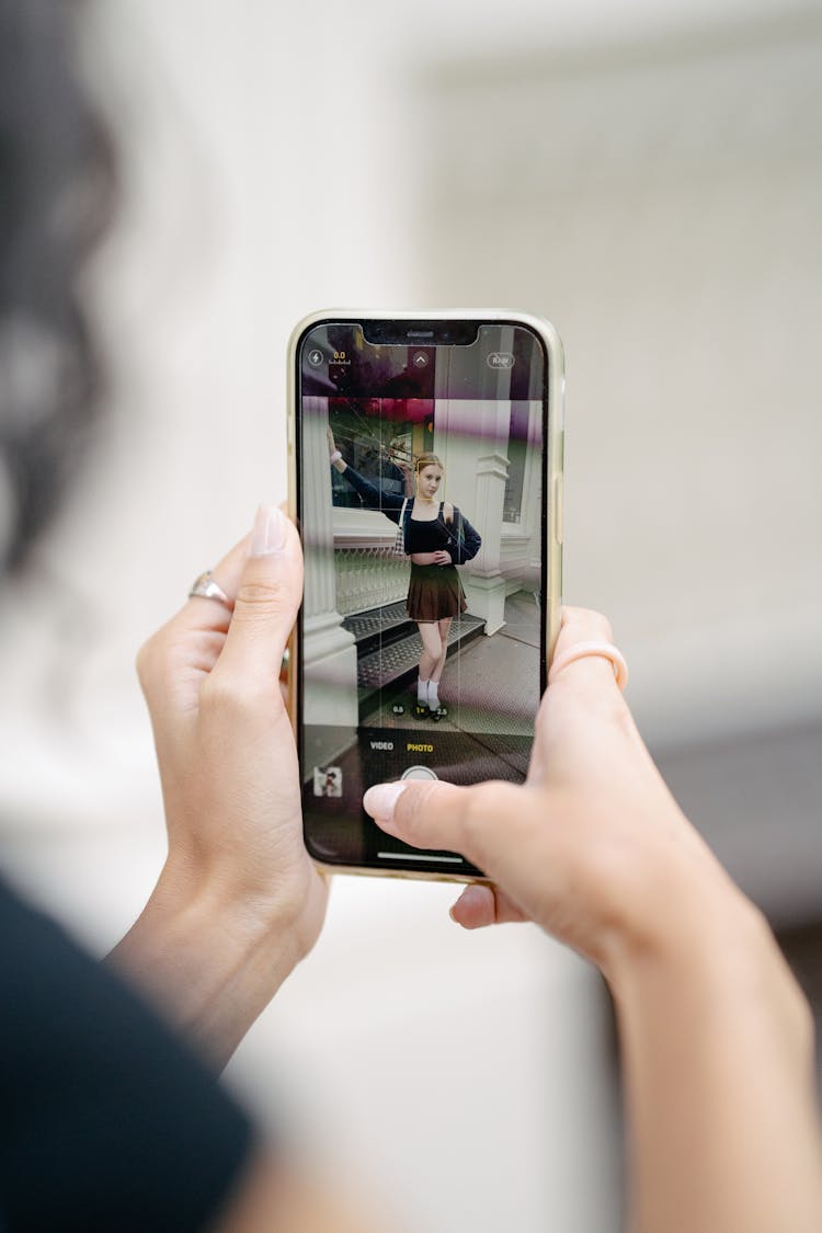 Hands Holding Phone Taking Photo Of Woman