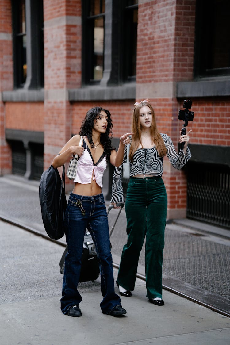 Young Girls Walking In City With Luggage And Camera On A Tripod 