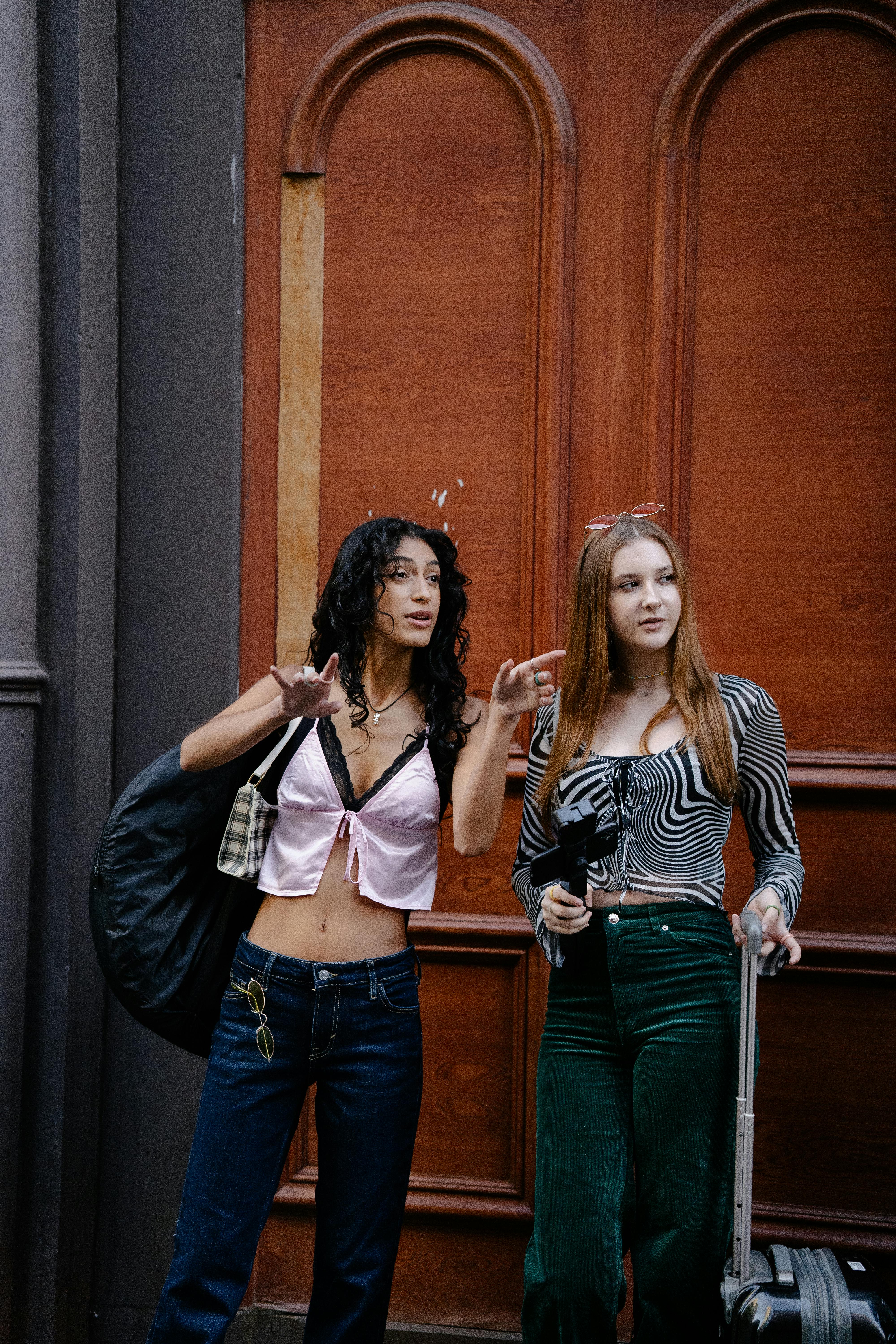 young girls walking in city with luggage and camera on a tripod