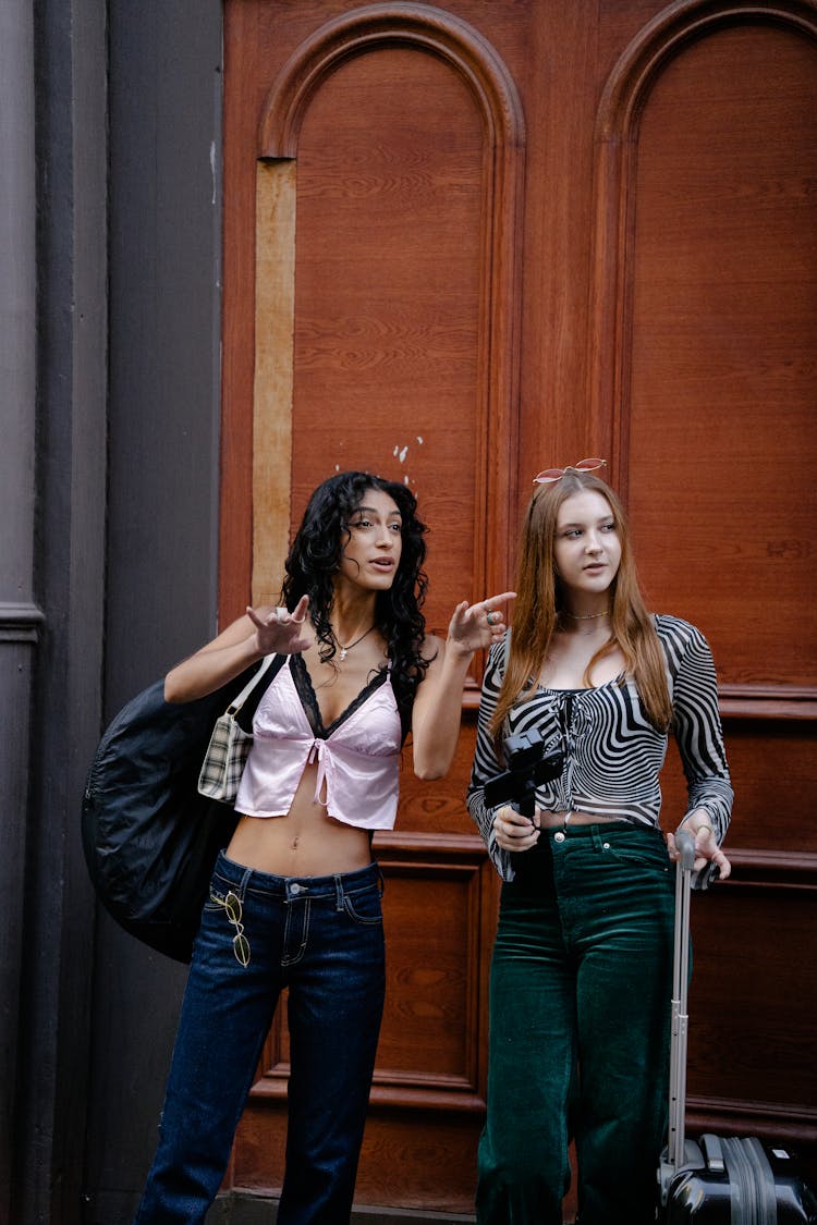 Young Girls Walking In City With Luggage And Camera On A Tripod 