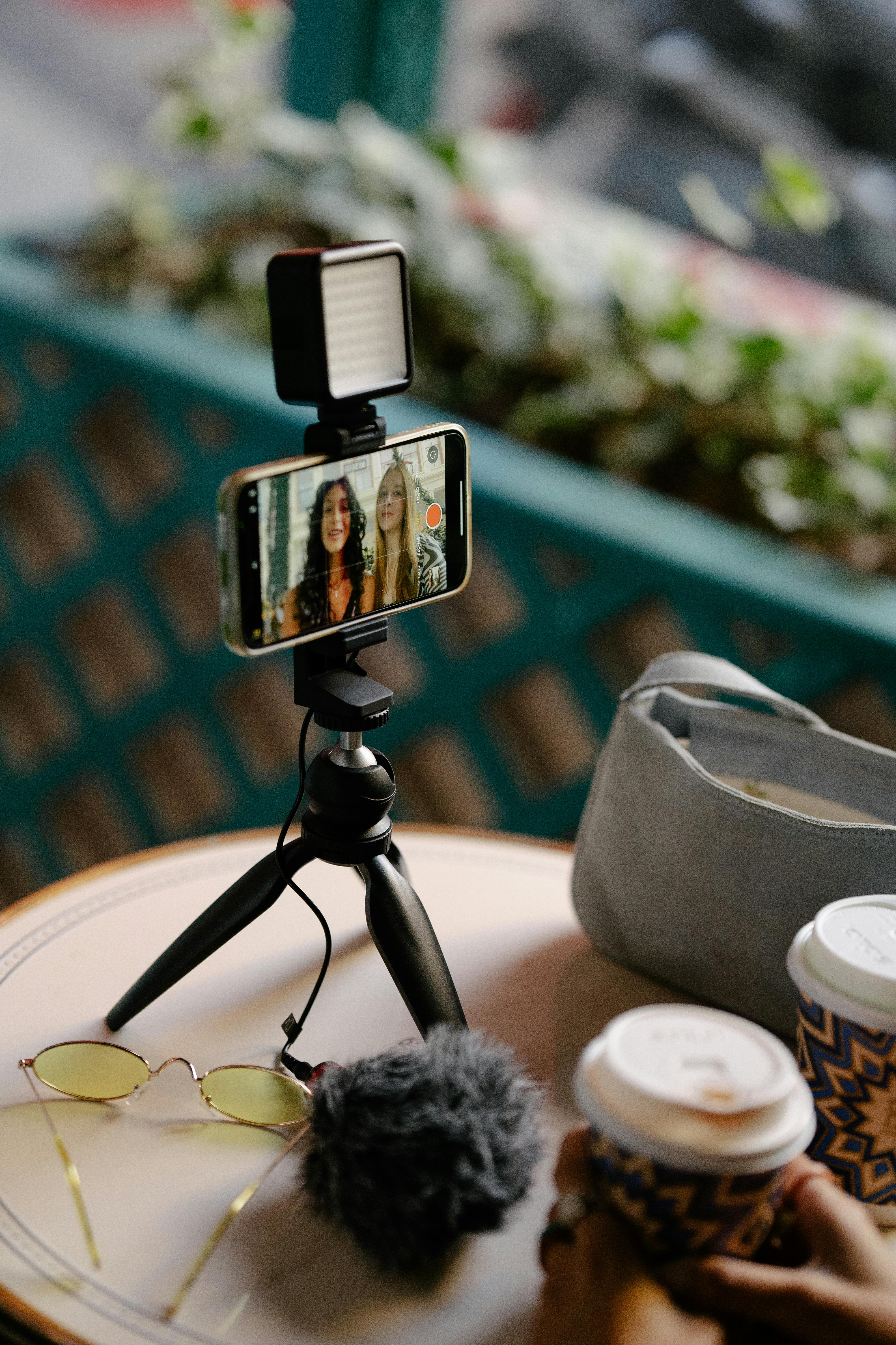 young girls recording themselves with a smartphone on a tripod in a cafe