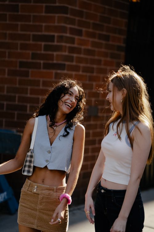 Free Young women enjoying a sunny day outdoors in a trendy urban setting, showcasing stylish outfits. Stock Photo