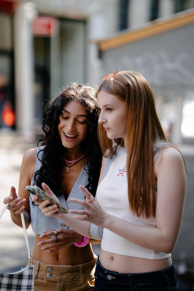 Women Standing In The City Street And Looking At A Smart Phone Screen