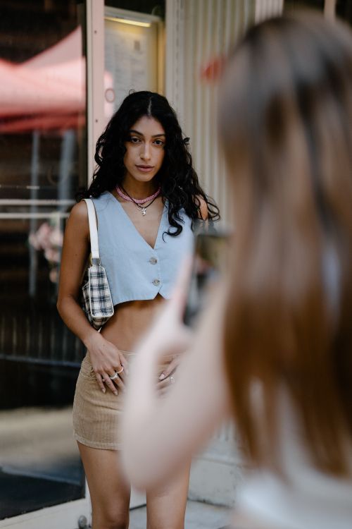 Free Young woman striking a pose in trendy outfit on a city street, captured in natural light. Stock Photo