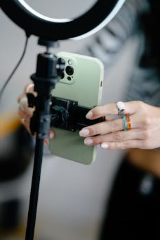 A woman adjusts a smartphone on a tripod with ring light for photography.