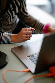 A woman working on a laptop with a USB cable connection, showing focus and productivity.