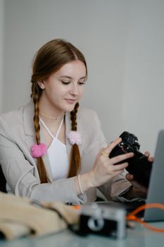 Smiling young woman photographer handling a DSLR camera while indoors, showcasing creativity in digital media.