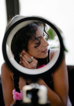 Captivating portrait of a woman braiding hair through a ring light, exuding elegance and style.