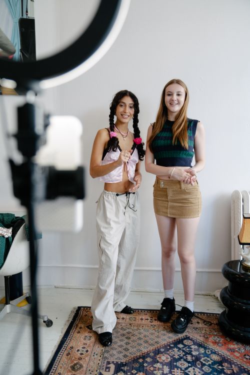 Free Two young women posing for a smartphone photo indoors with a ring light. Stock Photo