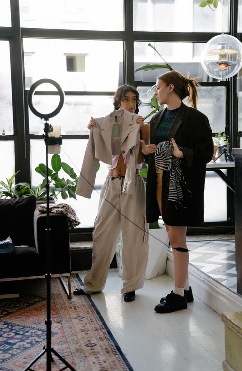 Free Two women styling outfits in a contemporary studio setting with natural light. Stock Photo