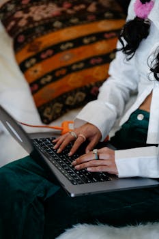 A woman typing on a laptop in a cozy indoor setting, showcasing focus and work.