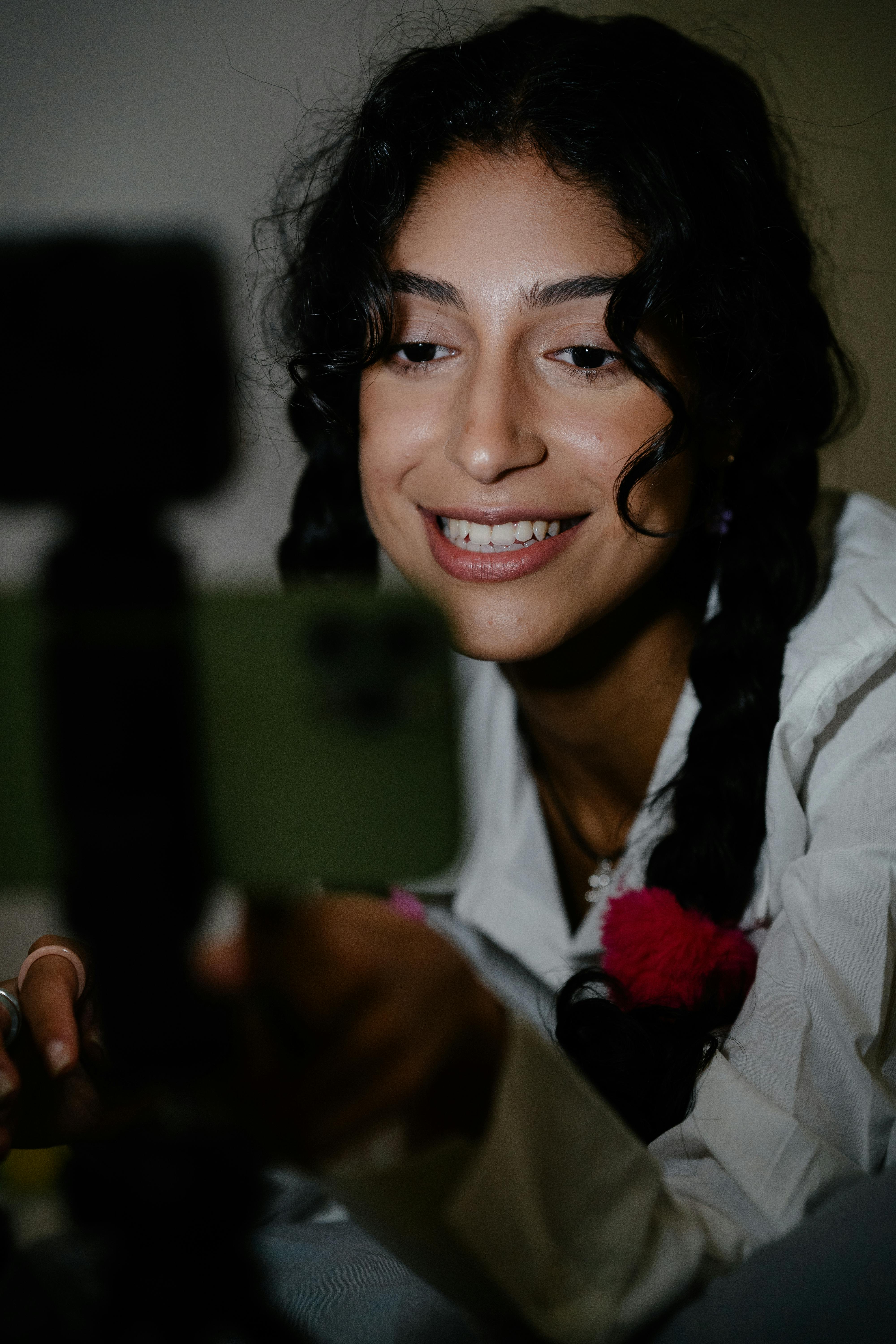 A cheerful woman with braids smiling during a video call indoors.