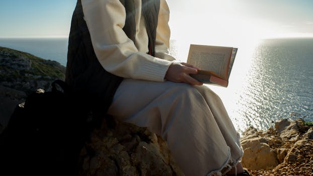 A serene moment captured as an individual reads by the ocean cliffs at sunset in Sesimbra, Portugal.