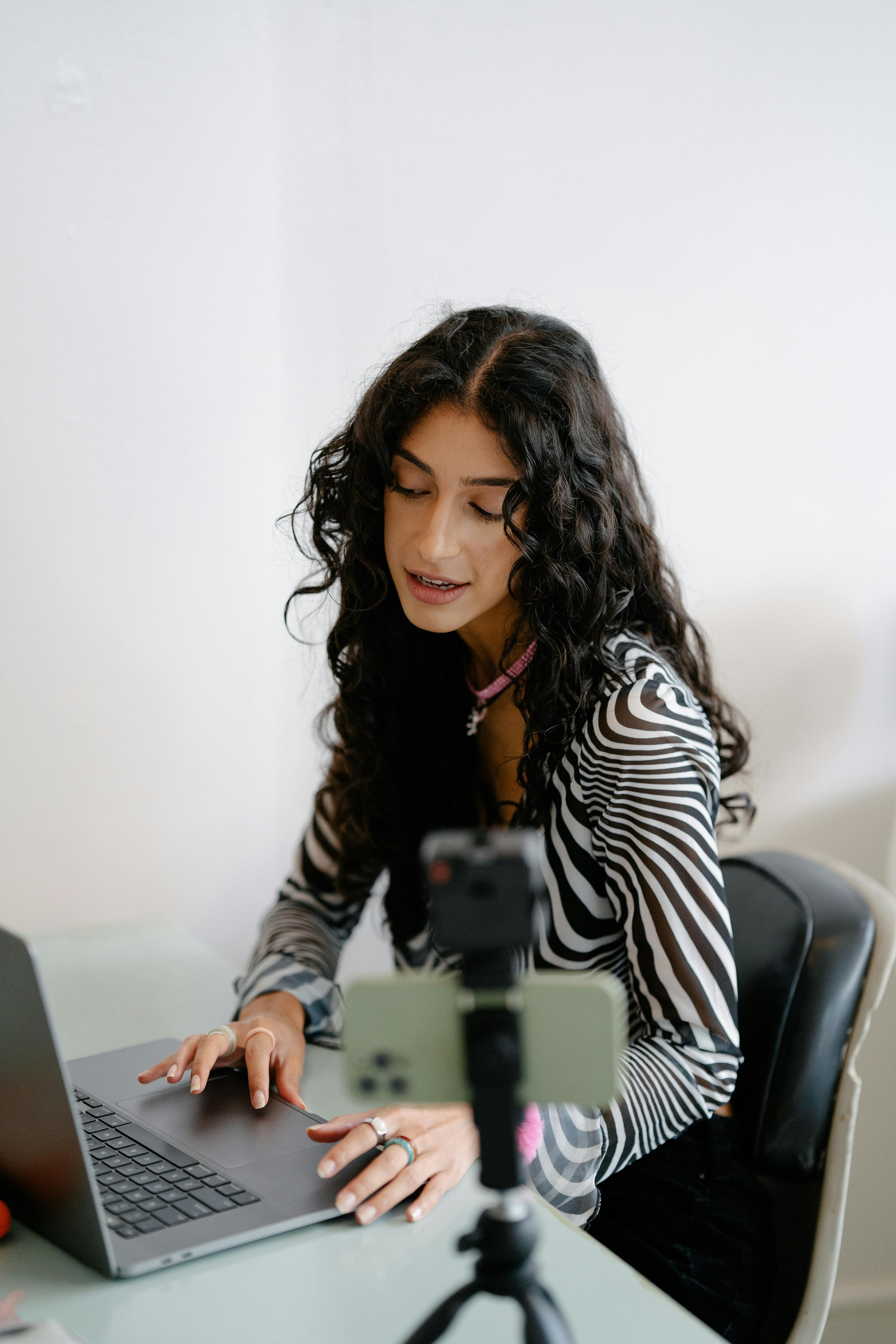 woman using laptop and smartphone on tripod