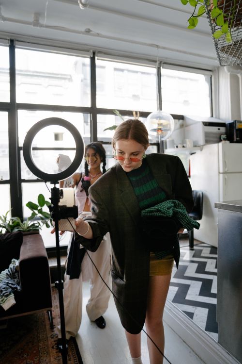 Free Two women engaged in an indoor fashion shoot with modern attire and lighting equipment. Stock Photo