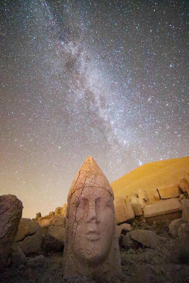 Ancient Head Sculpture Under Stars On Sky