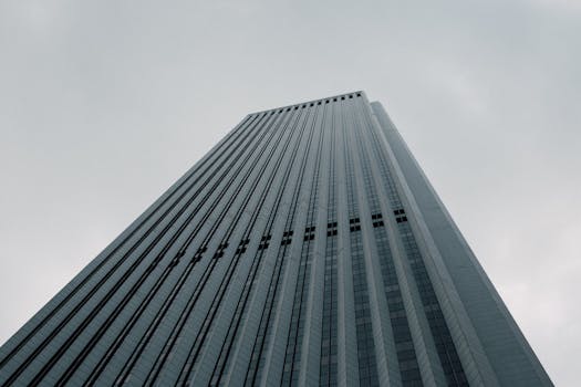 A low-angle view of a modern skyscraper reaching towards an overcast sky, showcasing architectural elegance.