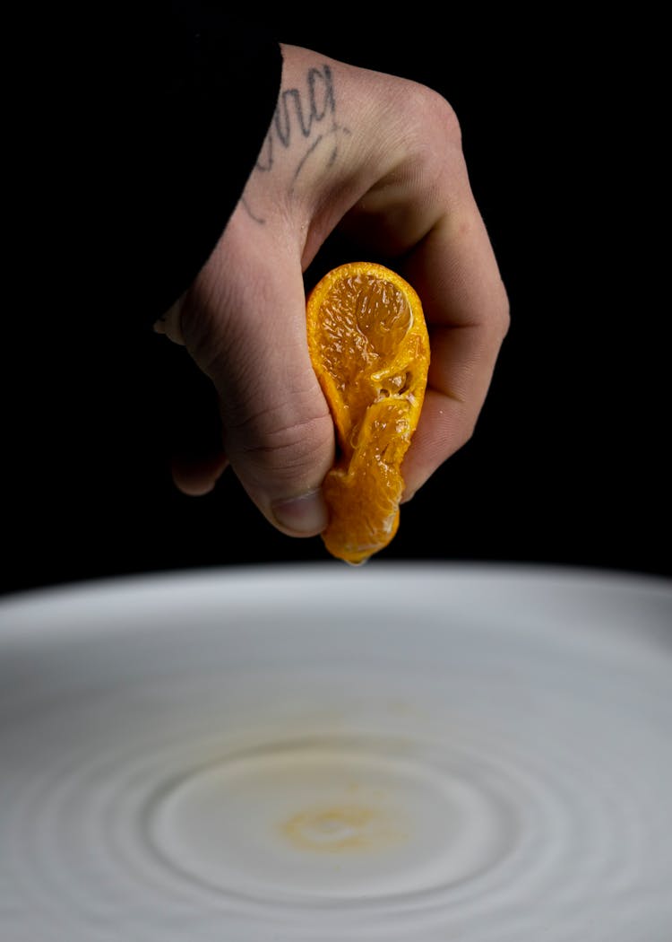 A Person Squeezing An Orange 