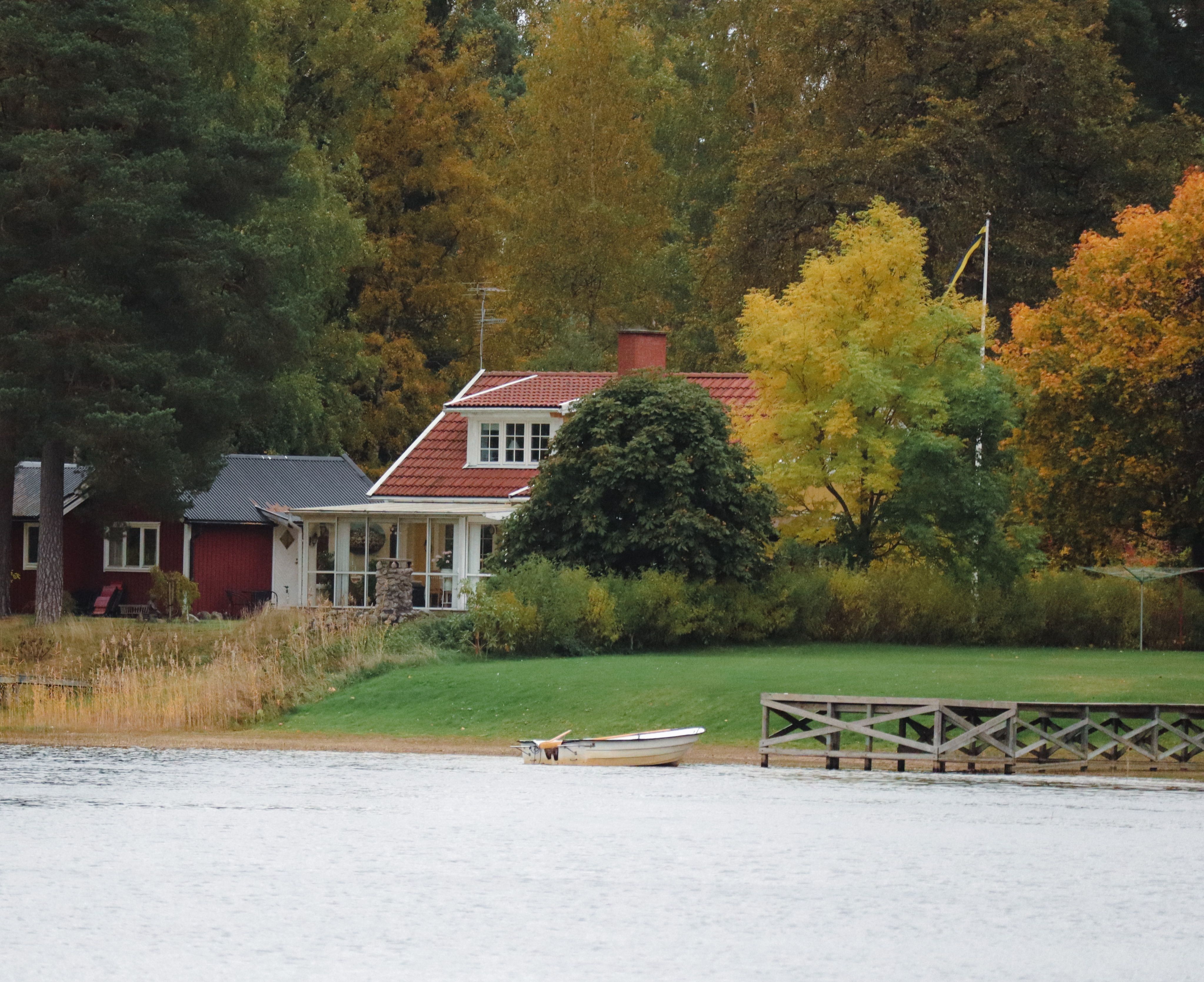 Lakeside cottage with a wooden dock and autumn foliage, representing riverfront cabins near the St. Croix