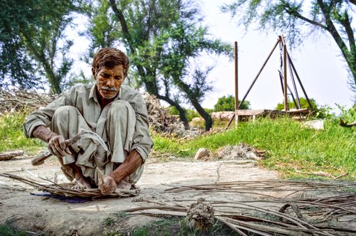 Free Elderly man working skillfully with wooden sticks in a park setting in Mian Channu, Punjab, Pakistan. Stock Photo