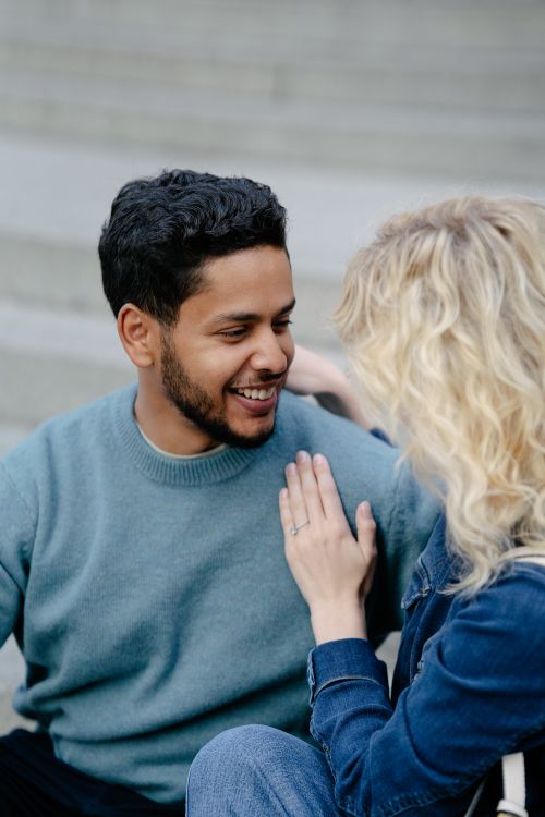 Free A happy couple smiling and sitting together on city steps, capturing a moment of joy. Stock Photo