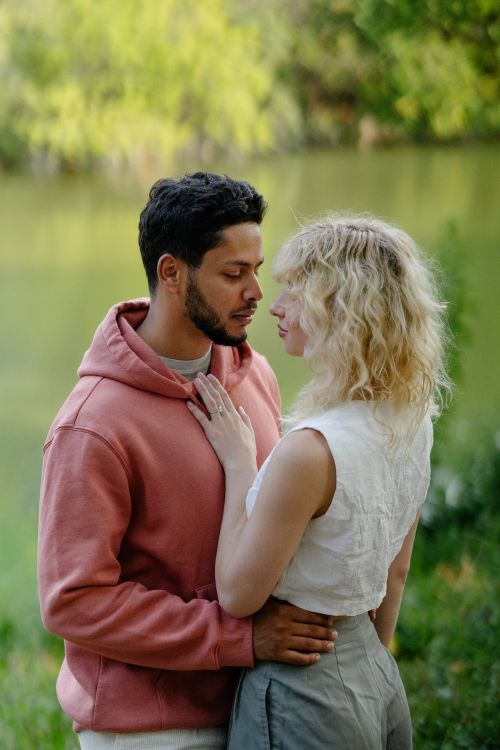 Free Young couple embraces near a scenic riverbank, conveying love and intimacy. Stock Photo