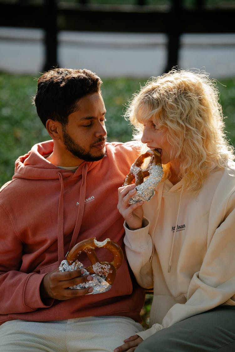 Woman And Man Sitting And Eating Pretzels