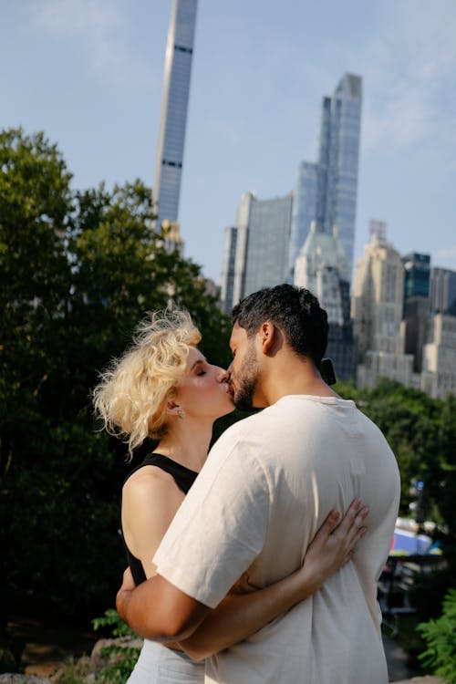 Couple Kissing in Park with Skyscrapers in Background