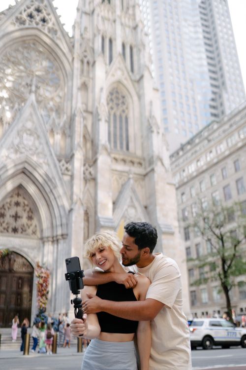 Free Happy couple embracing in front of a historic cathedral, capturing fun memories. Stock Photo