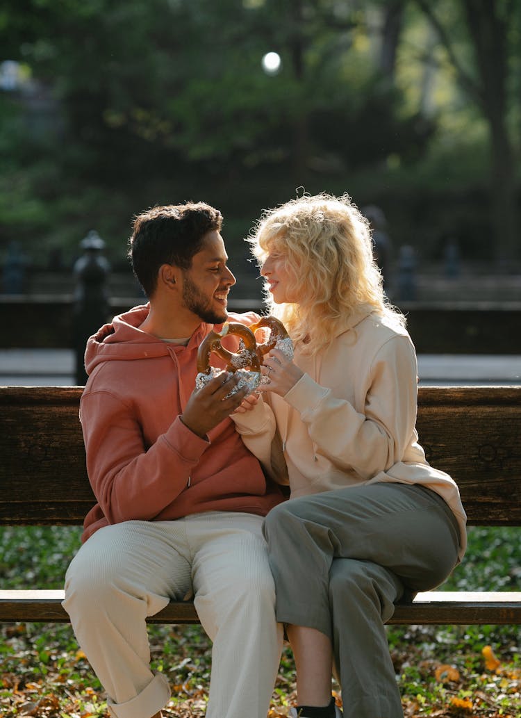 Couple Eating Pretzels On Bench