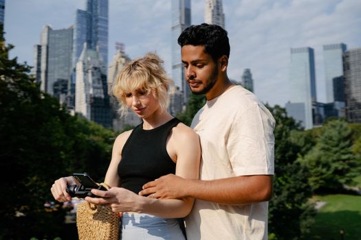 A couple standing together in a city park with skyscrapers in the background, capturing memories.