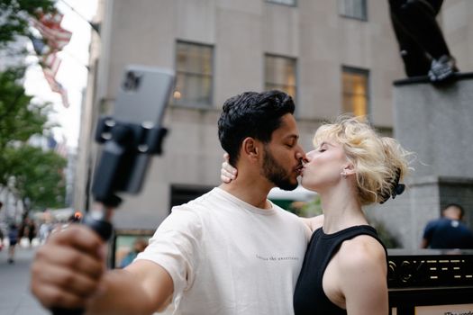 Brunette Man Taking a Selfie while Kissing a Blond Woman