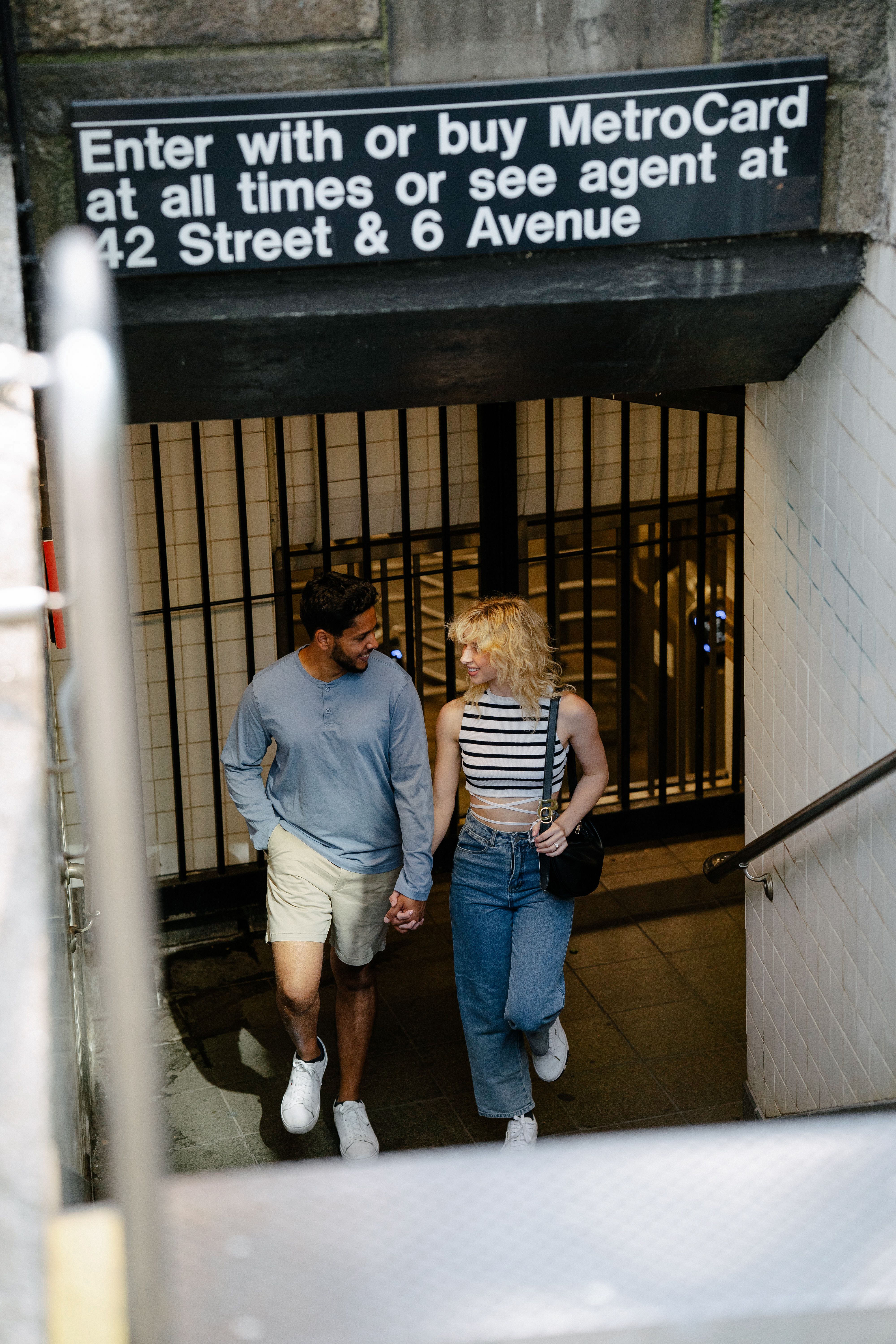 Romantic couple holding hands while entering NYC subway station at 42 Street & 6 Avenue.