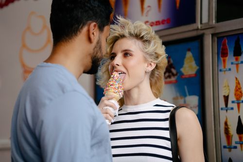 Free A couple playfully shares an ice cream cone with sprinkles, capturing a moment of romance and fun. Stock Photo